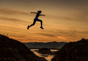 Athletic Woman Jumping High Into the Air at Sunset